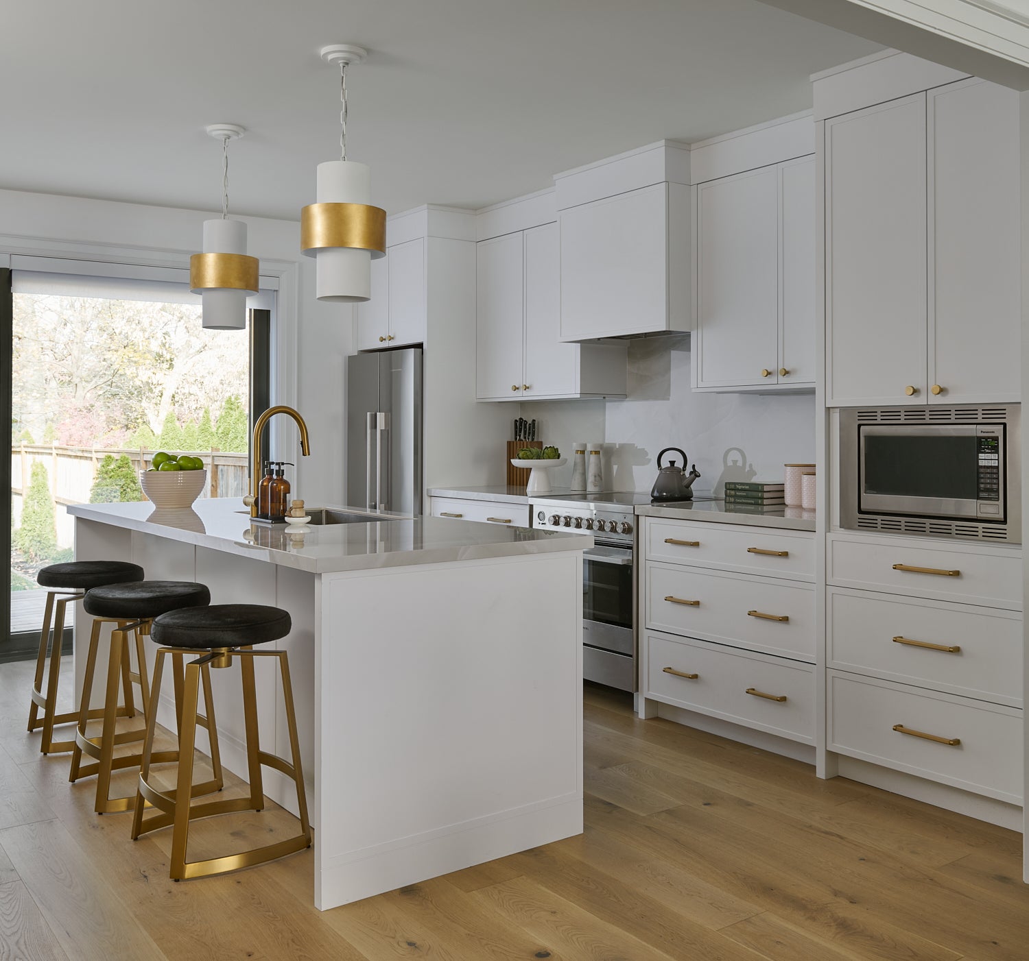 Transitional home white kitchen with brass hardware faucet and accents with black pony fur counter stool contemporary lighting