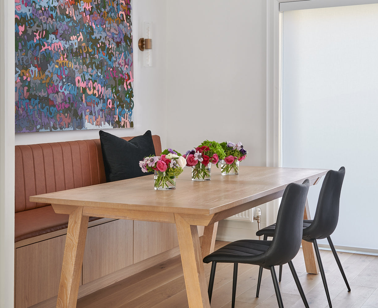 White oak wood table with modern and sleek design and banquette seating with black leather chairs and contemporary modern art