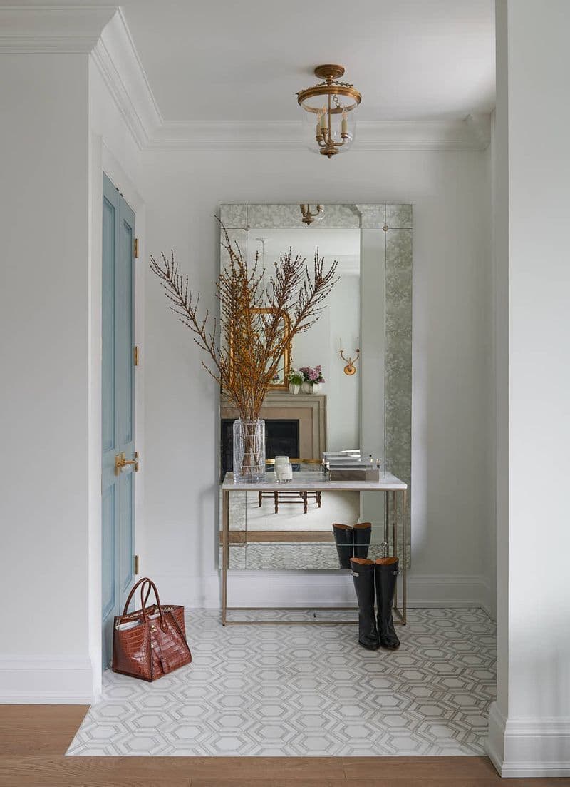 A softly styled entryway — mirrored console, brass lantern, forsythia branches
