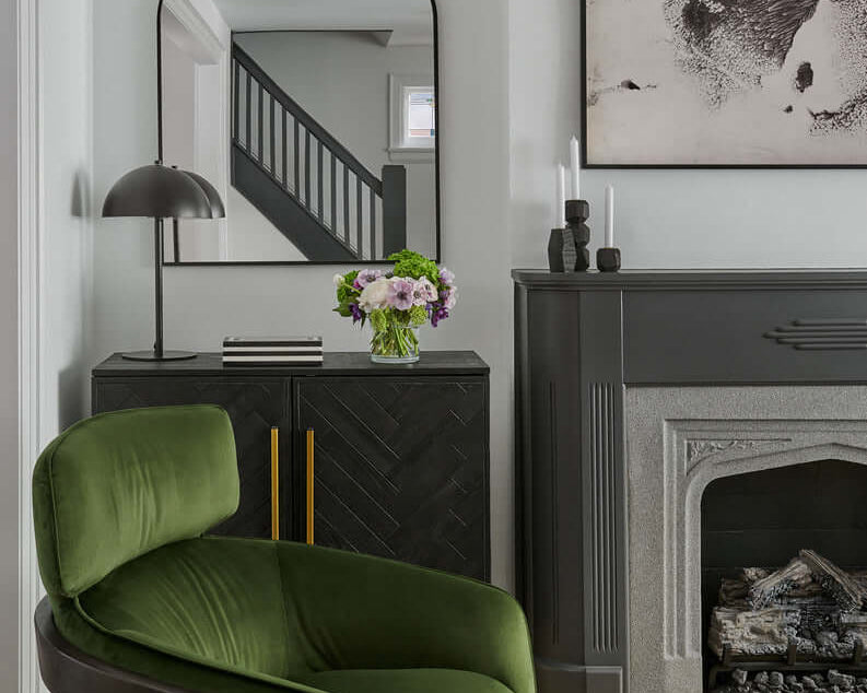 Contemporary living room with black and white stripe rug hunter green velvet accent chairs black cement coffee table and cognac leather tufted sofa