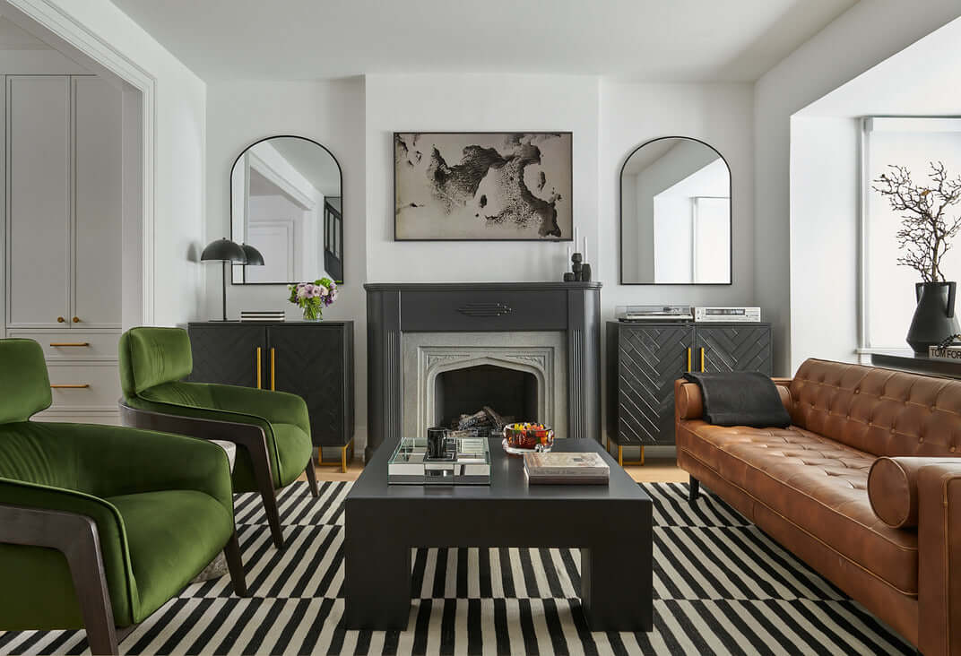 Contemporary living room with black and white stripe rug hunter green velvet accent chairs black cement coffee table and cognac leather tufted sofa