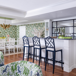 Green hollywood palm wallpaper with coral style dining chairs and gold palm chandelier Naples Florida home colorful playful style decor navy blue lacquer counter stools Chippendale style