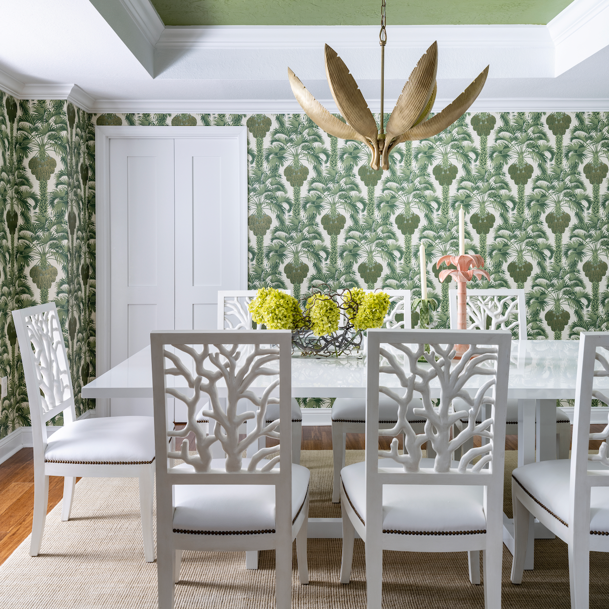 Green hollywood palm wallpaper with coral style dining chairs and gold palm chandelier Naples Florida home colorful playful style decor