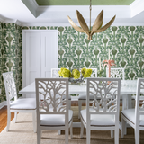 Green hollywood palm wallpaper with coral style dining chairs and gold palm chandelier Naples Florida home colorful playful style decor